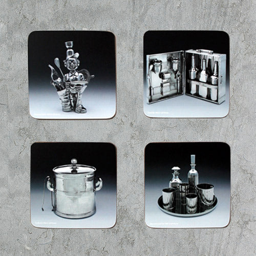 Selection of four cork backed coasters featuring Jeff Koons' Ice Bucket, Baccarat Crystal Set, Travel Bar, and Fisherman Golfer works
