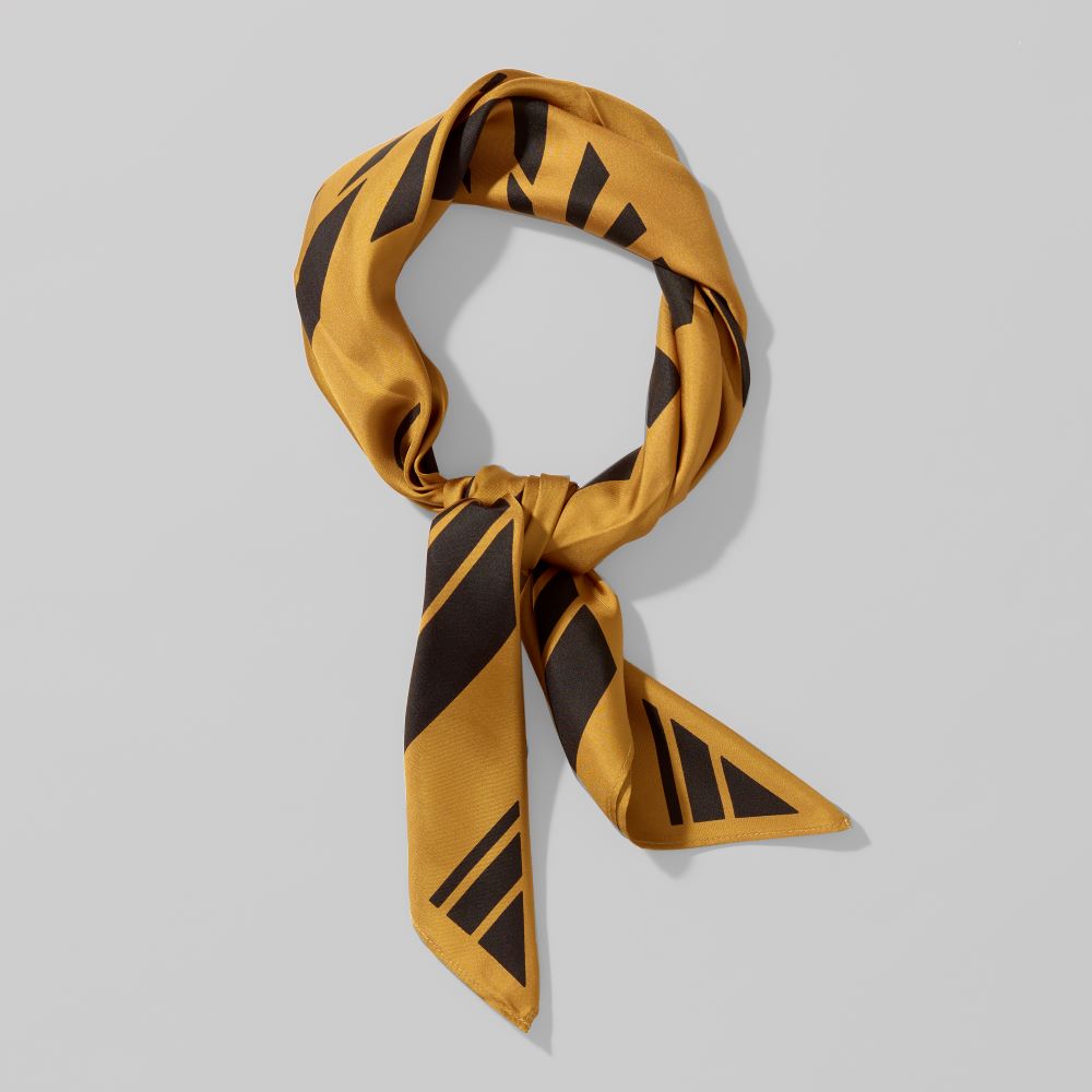 Folded 100% silk twill gold with black corridor scarf by Carol Bove. Measures 36" x 36"