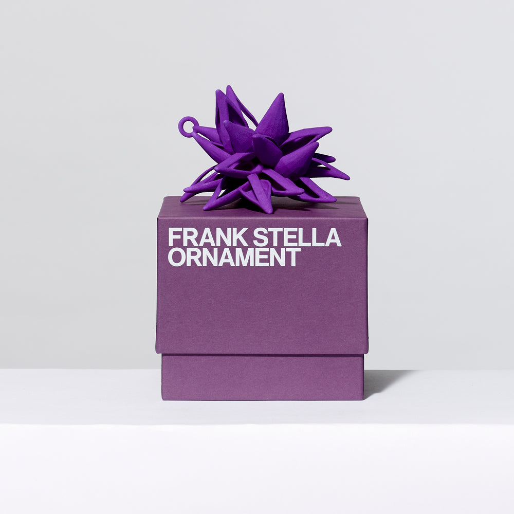 3-D printed plastic Frank Stella star ornament in purple on top of gift box. Measures approximately 4" x 4" x 4"