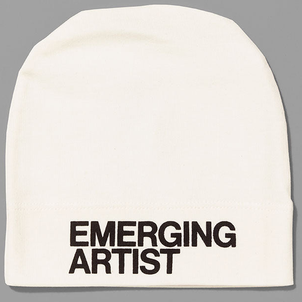 White beanie with 'EMERGING ARTIST' text on a gray background
