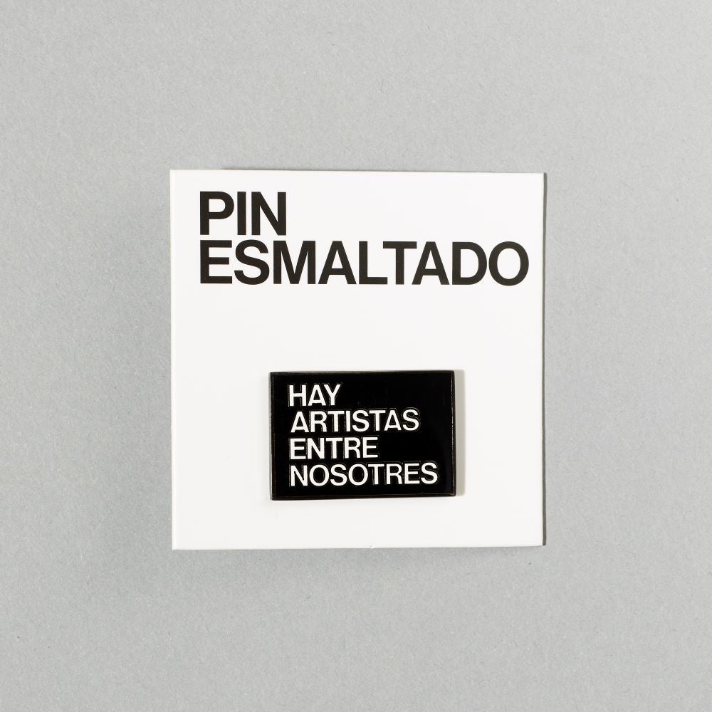 Black nickel plated brass and hard enamel pin that reads Hay Artistas Entre Nosotres