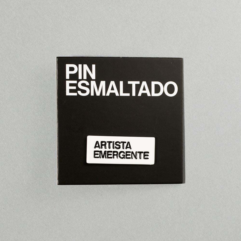 Black nickel plated brass and hard enamel pin that reads Artista Emergente