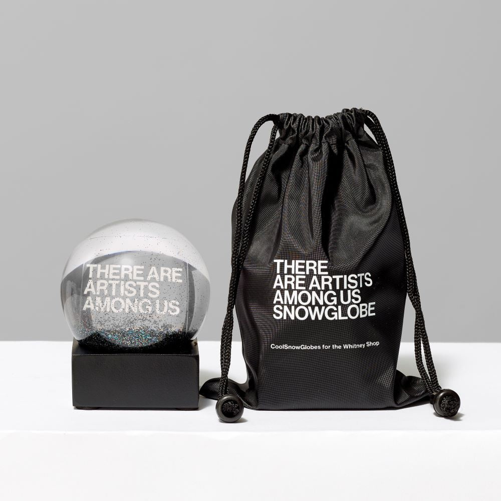 3 Fl oz. and 2.56" Snow Globe featuring the text "There Are Artists Among Us" standing next to an accompanying black pouch that reads "There Are Artists Among Us Snow Globe"