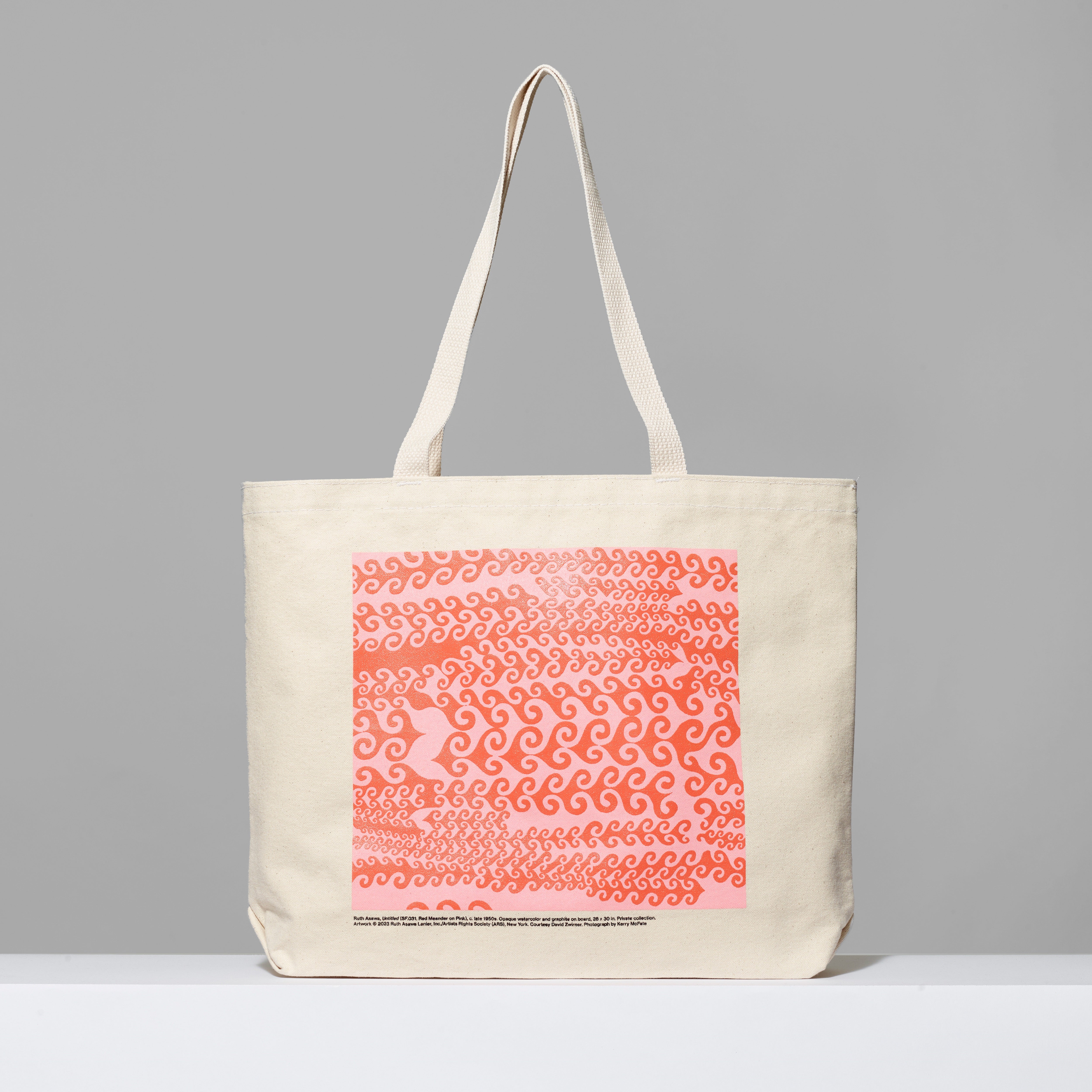 Beige tote bag with a pink and white pattern on a gray background, featuring Ruth Asawa's Untitled (SF .031, Red Meander on Pink