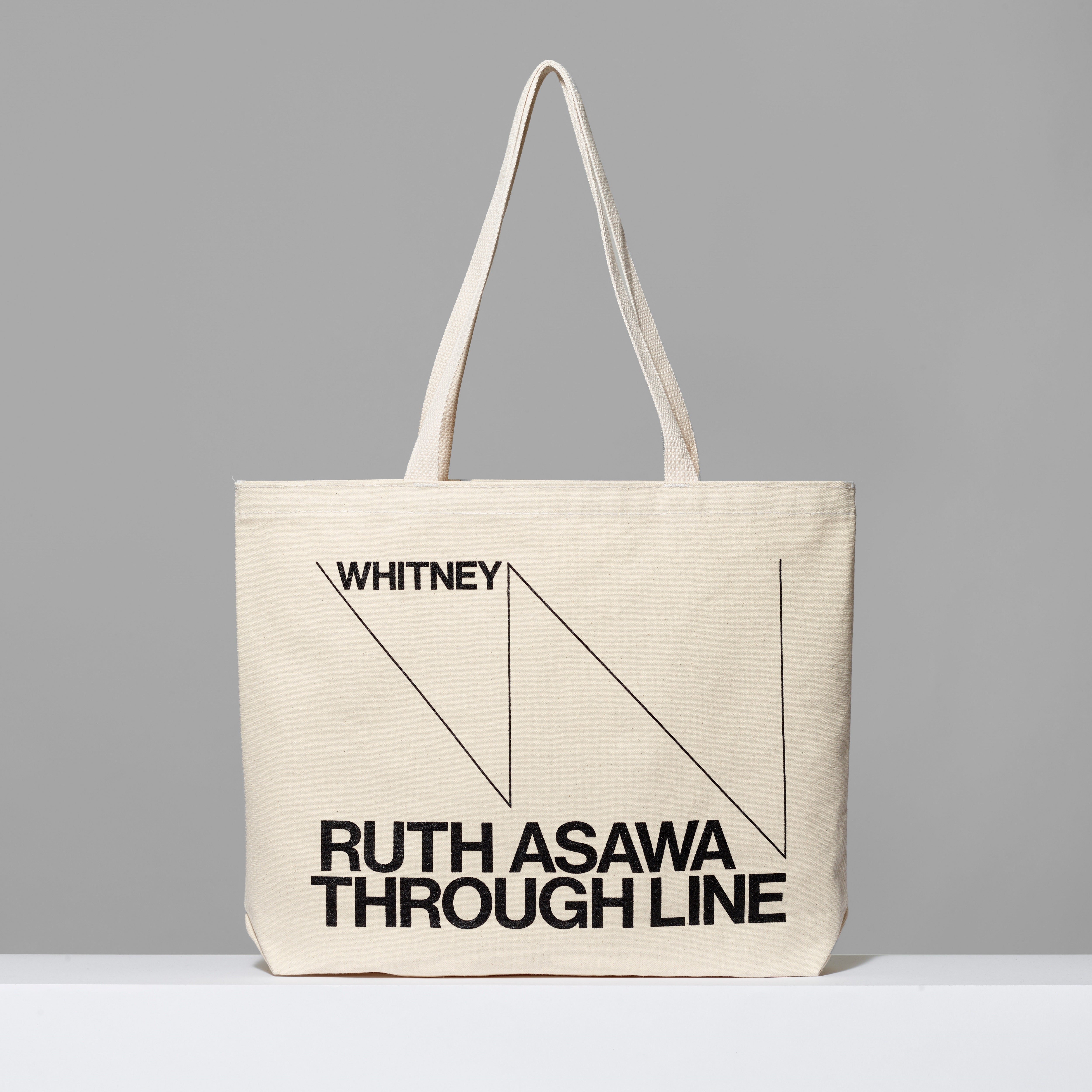 Beige tote bag with black text featuring Whitney and Ruth Asawa Through Line