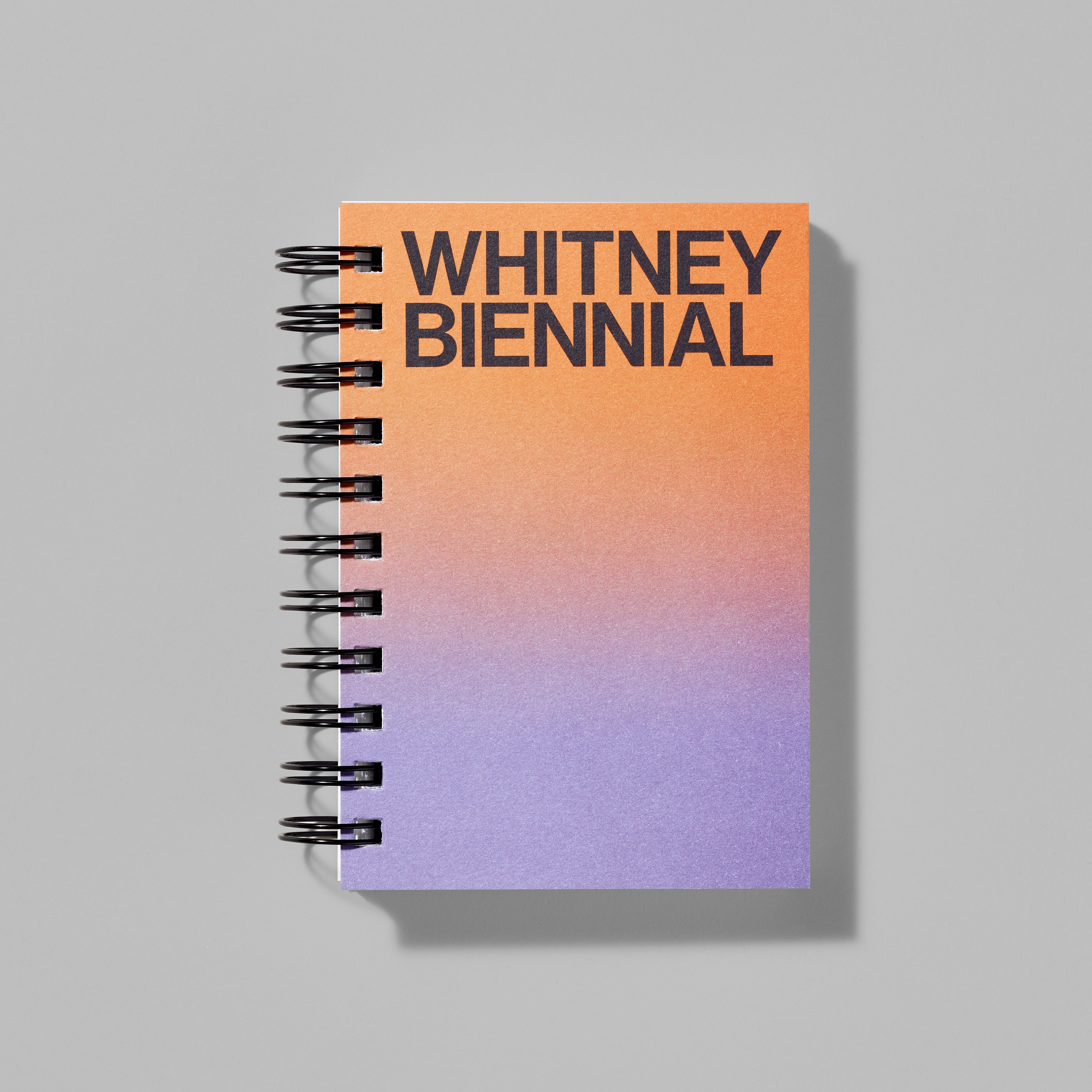 Purple and orange gradient spiral notebook featuring Whitney Biennial in black text
