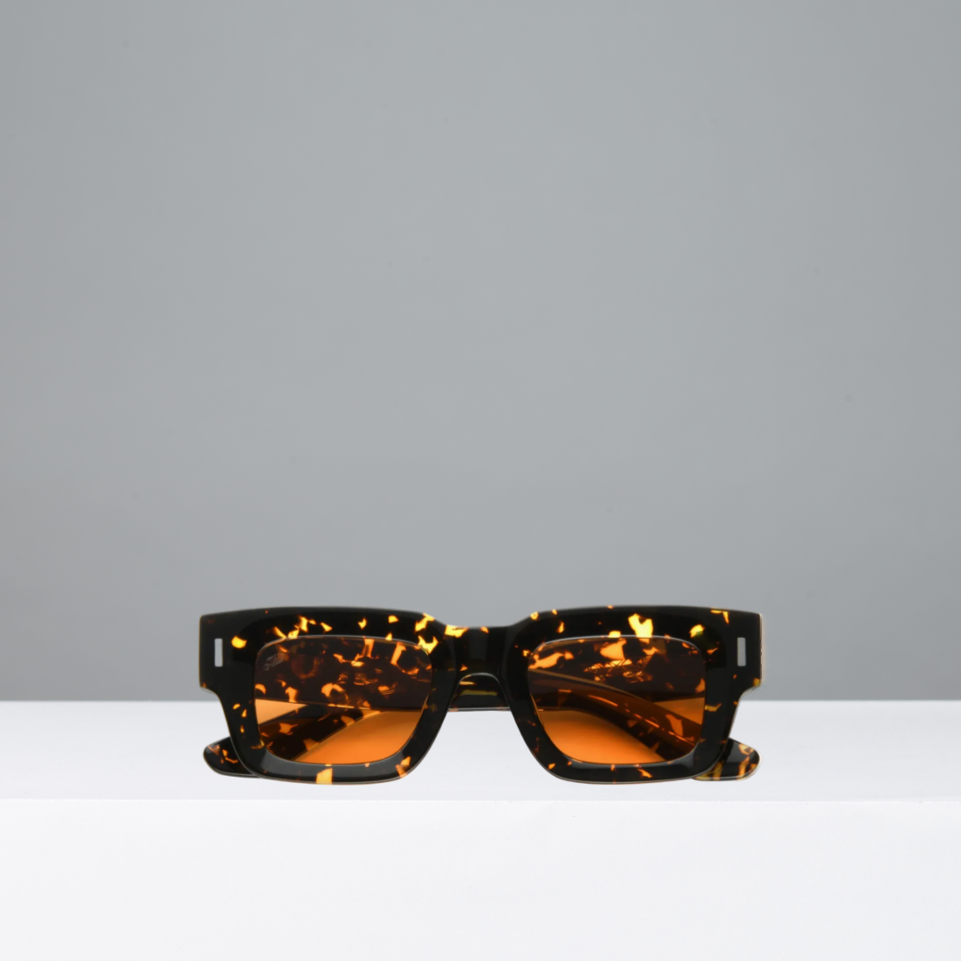 Tortoiseshell sunglasses with orange lenses on a gray background