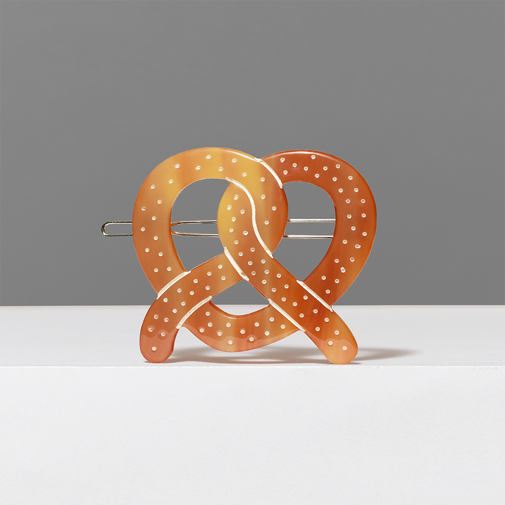 Decorative pretzel-shaped hair clip on a gray background