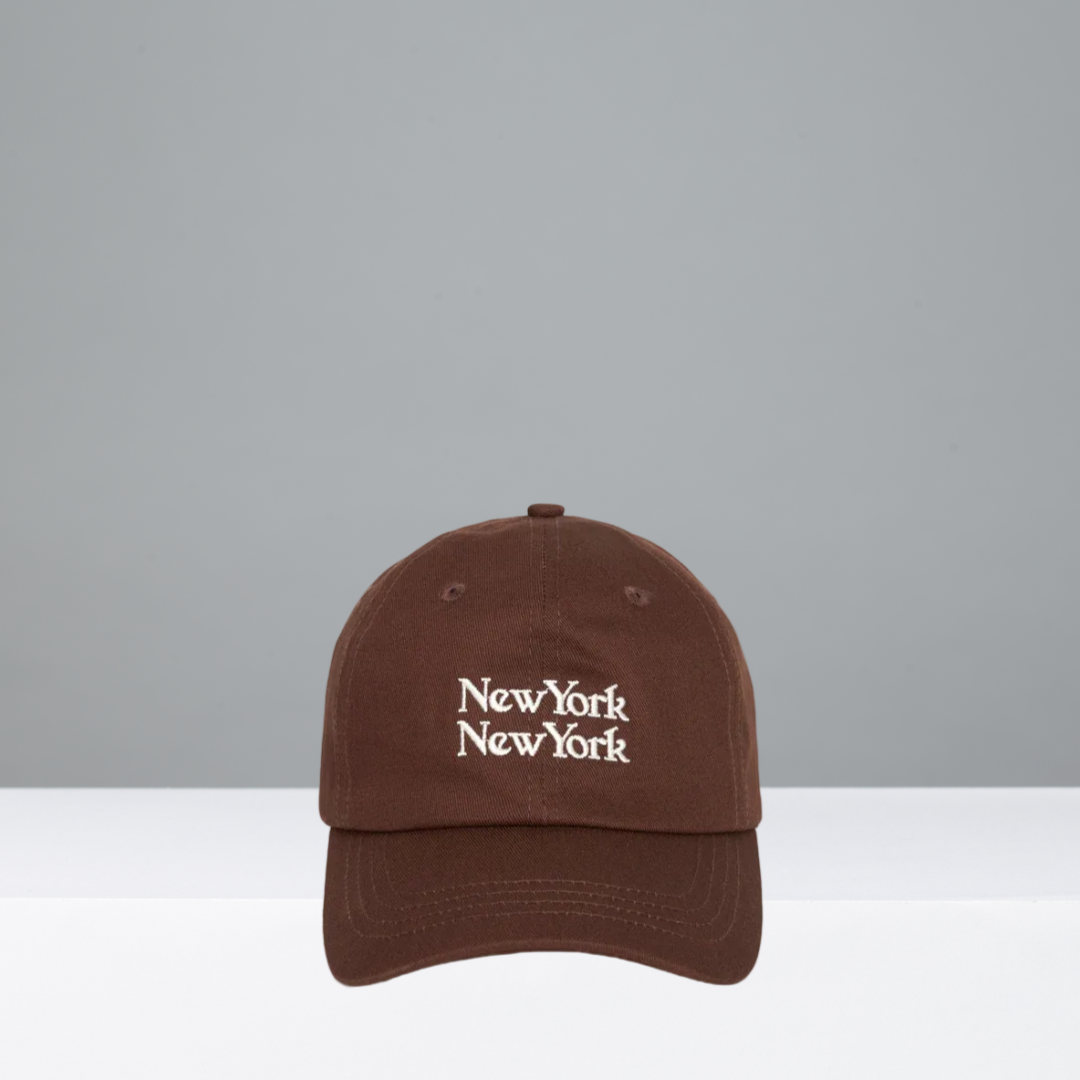 A brown baseball cap with 'New York New York' embroidered in white on the front, displayed against a neutral gray and white background.