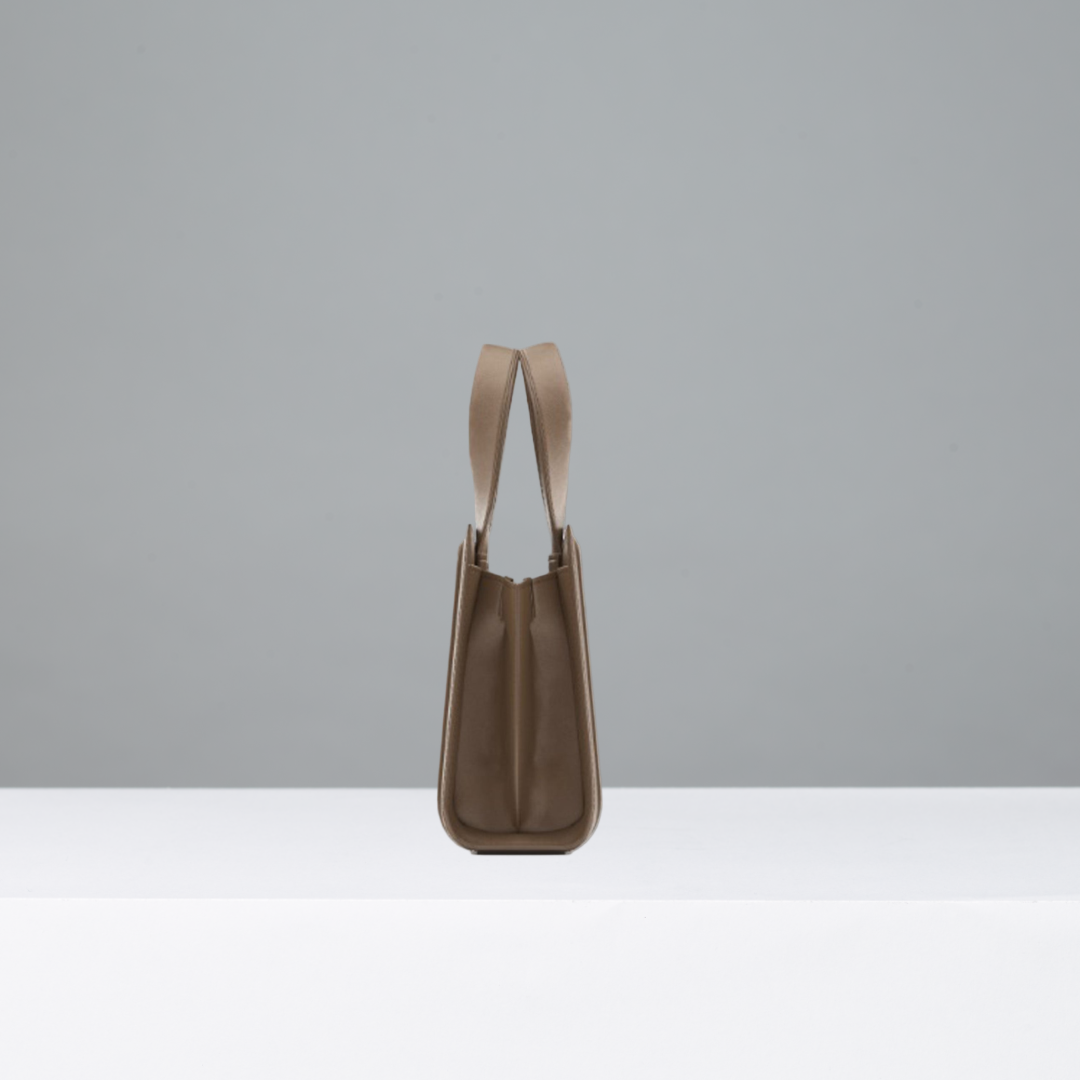 Side view of camel leather handbag with thin straps on a gray background