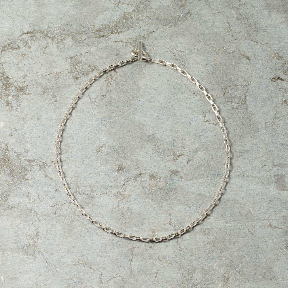 Silver chain necklace on a textured gray surface