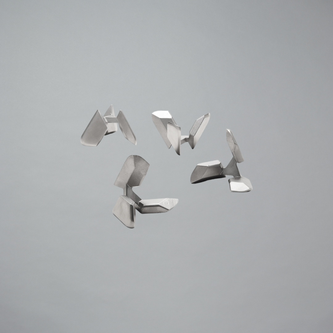 Set of four metallic geometric objects on a gray background