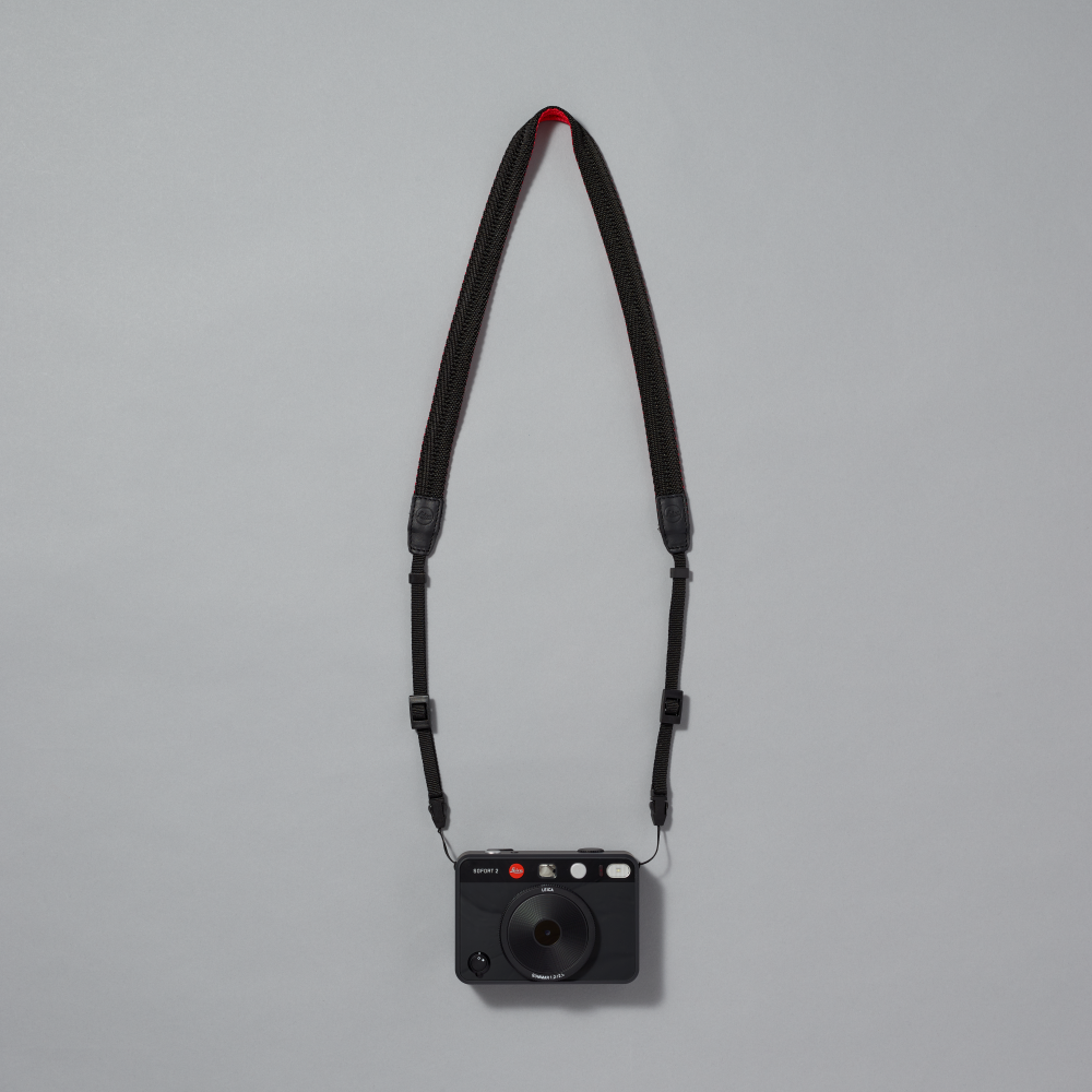Black camera with strap on a gray background