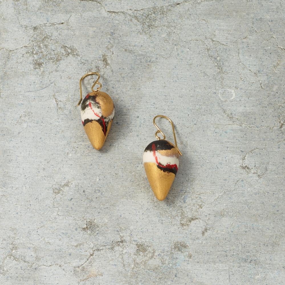 Pair of gold earrings with colorful designs on a textured gray surface