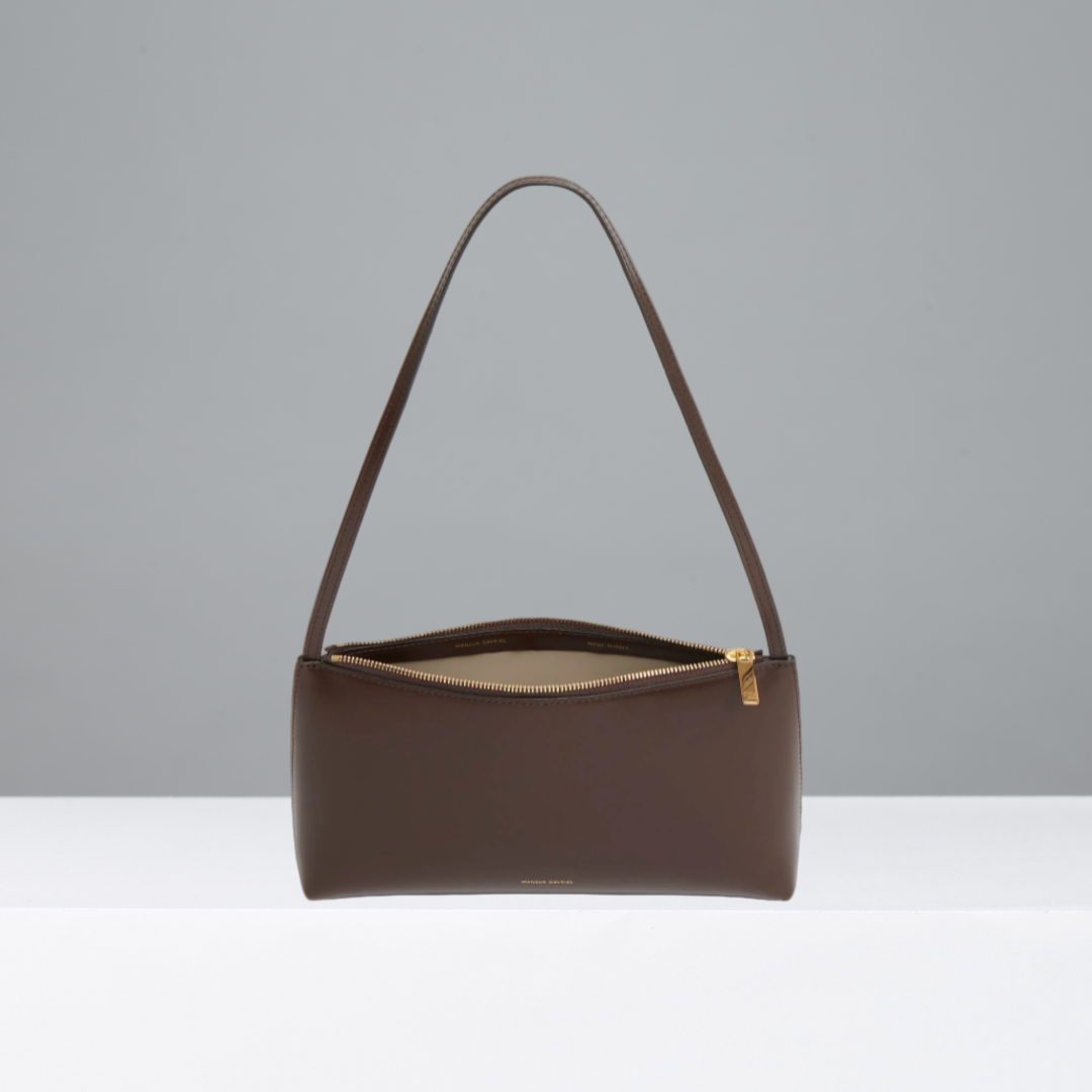 Brown handbag with a gold zipper on a gray background