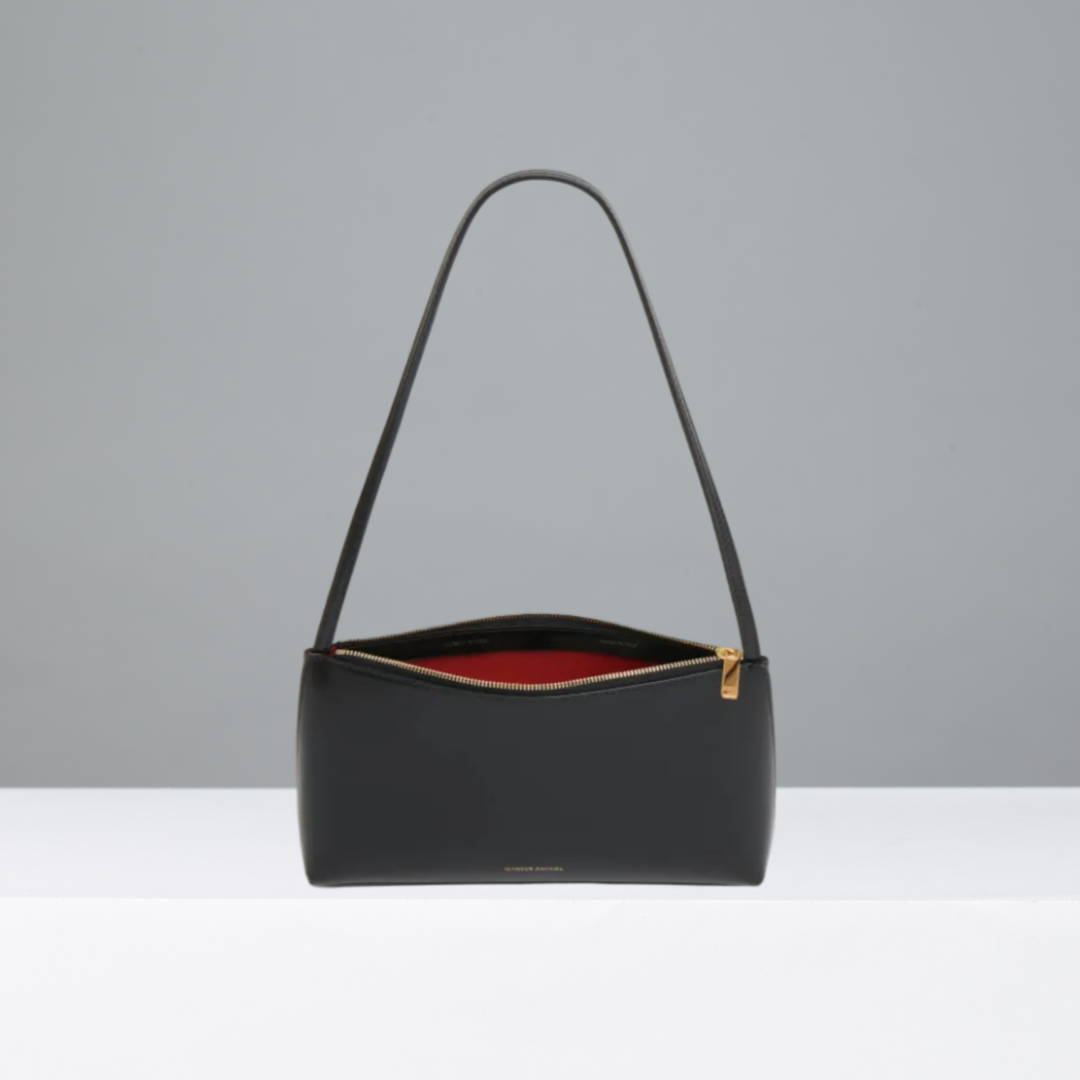 Black handbag with a red interior on a gray background