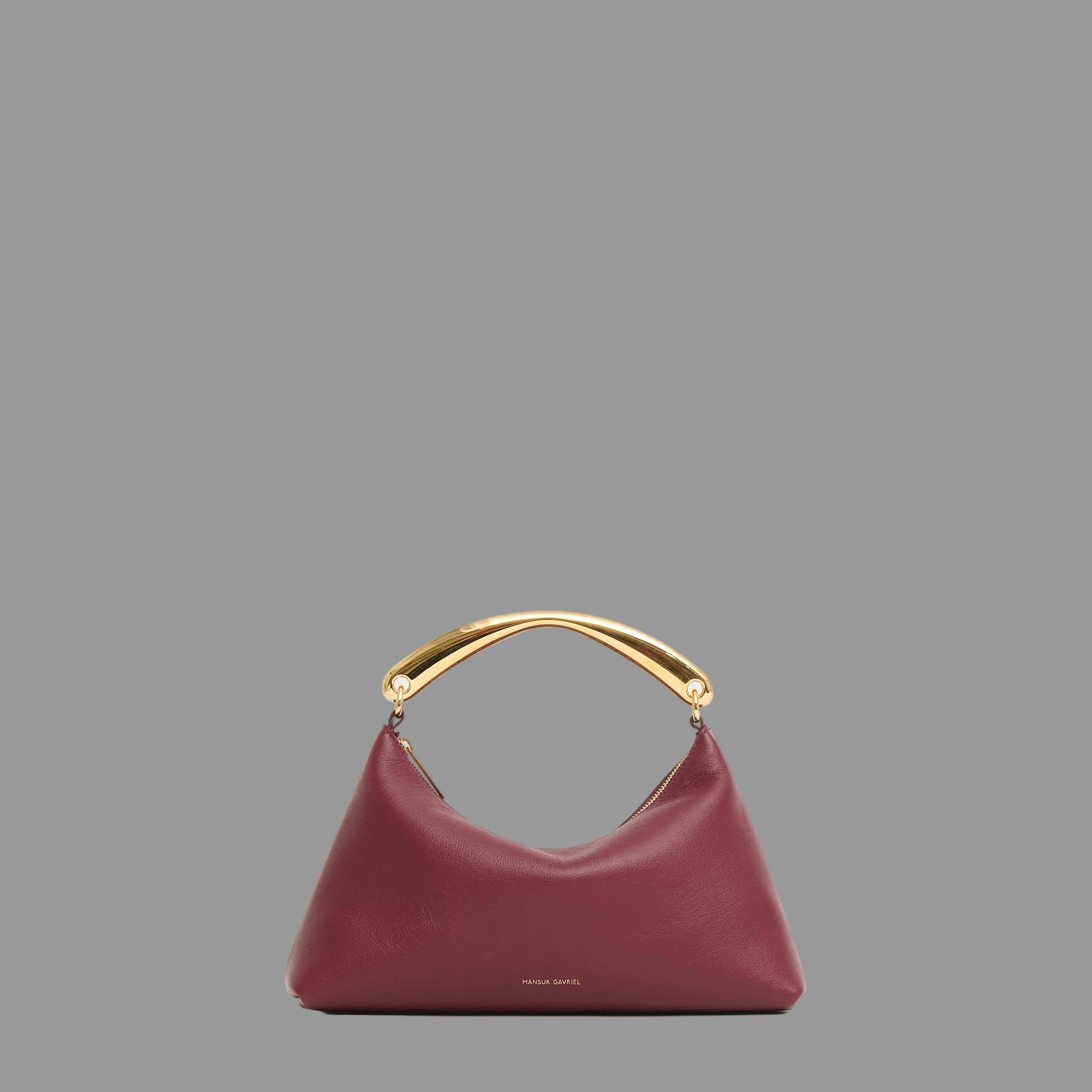 Oxblood red handbag with gold metal handle on a gray background