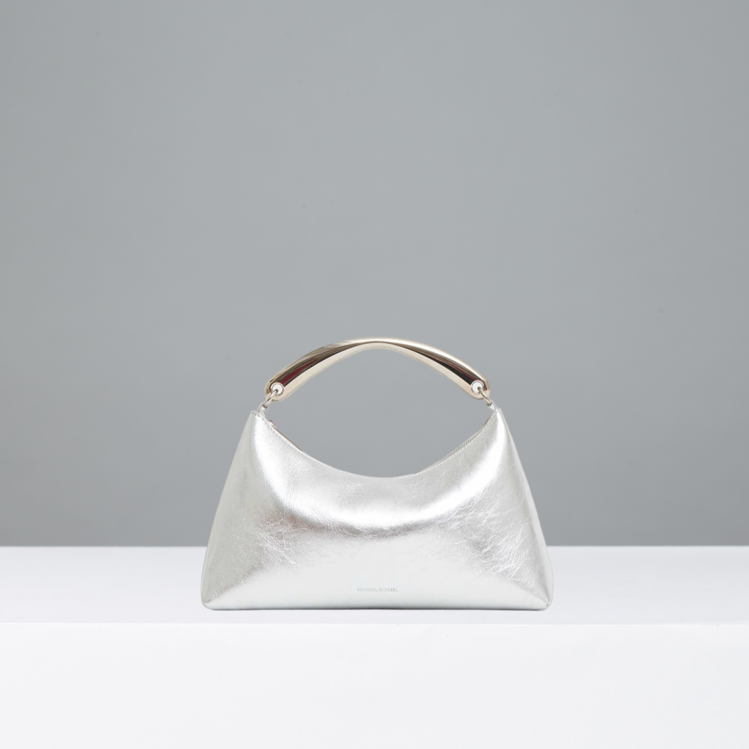 Silver handbag with silver metal handle on a gray background