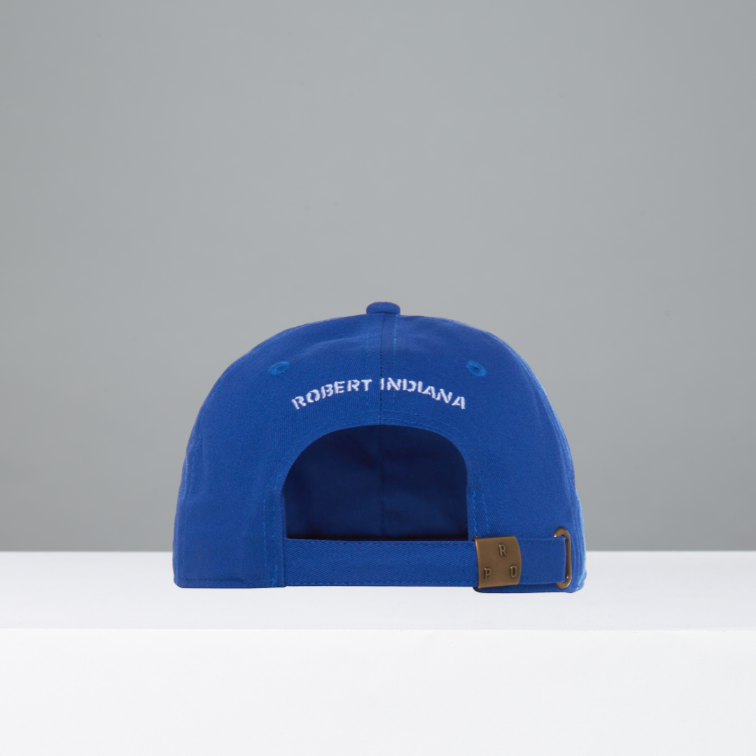 Back of blue colored cap with 'Robert Indiana' embroidered in white on a gray background