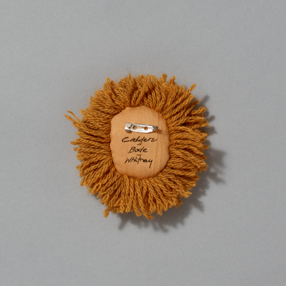 Brown yarn lion head with a barrette on a gray background