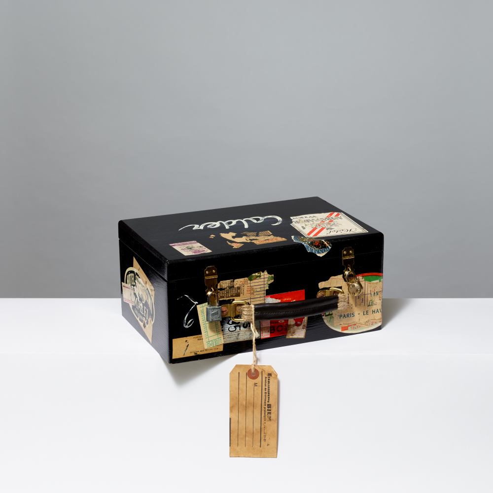 Decorative black box with vintage-style labels and a tag on a gray background