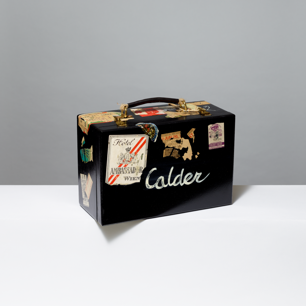 Black suitcase with travel stickers and 'Calder' branding on a gray background