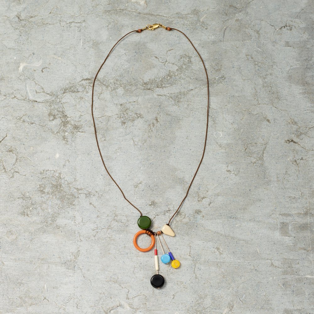 Necklace with colorful pendant on a textured gray surface