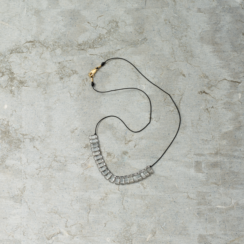 Necklace with clear beads on a textured gray surface