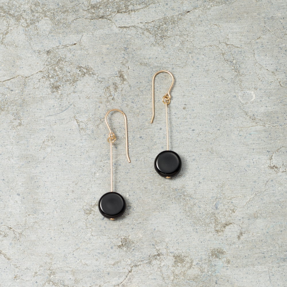 Pair of black earrings on a textured gray surface