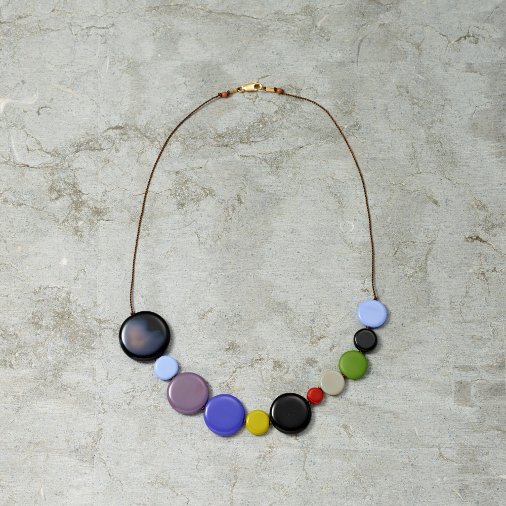 Necklace with colorful round beads on a textured gray background