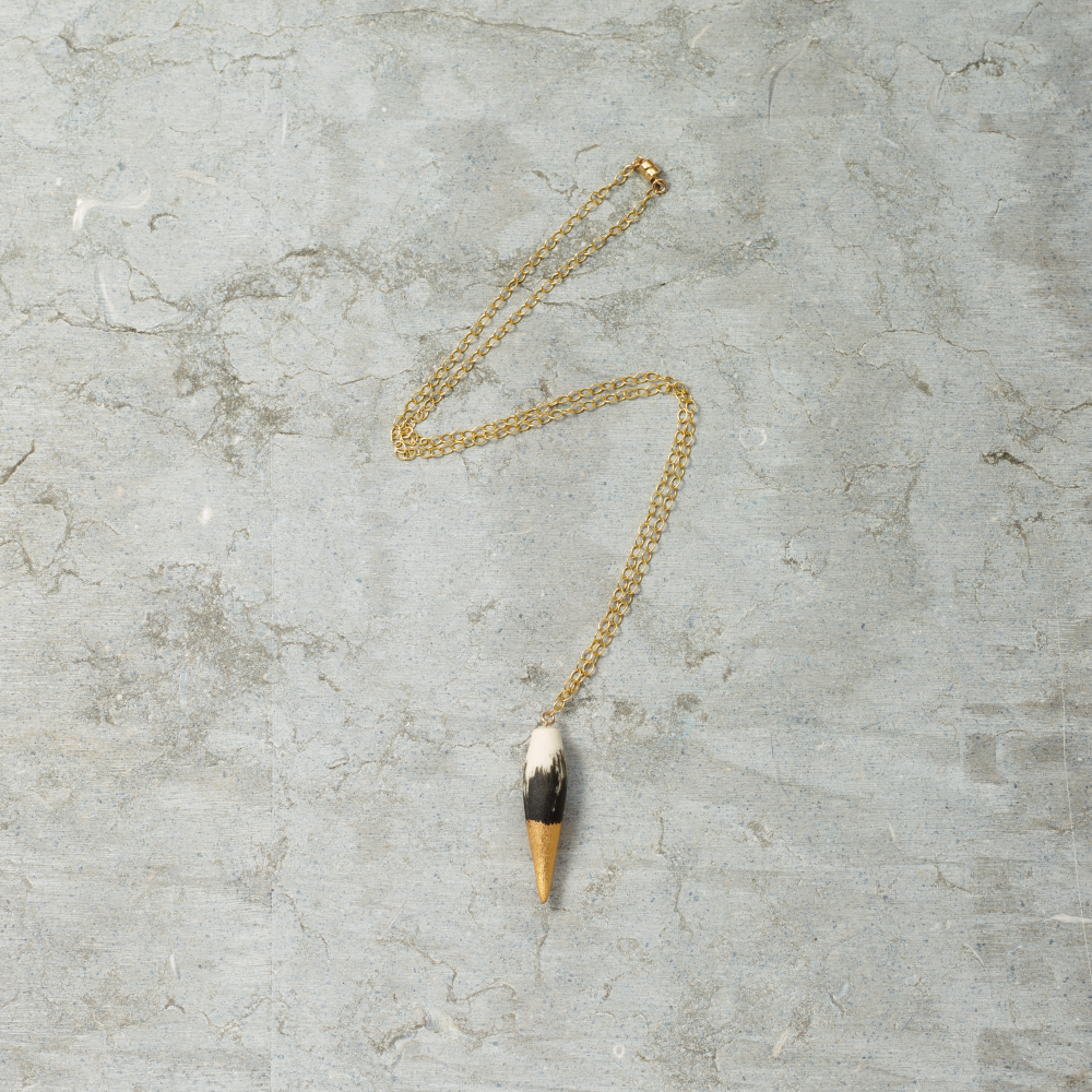 Gold necklace with a unique pendant on a textured gray surface