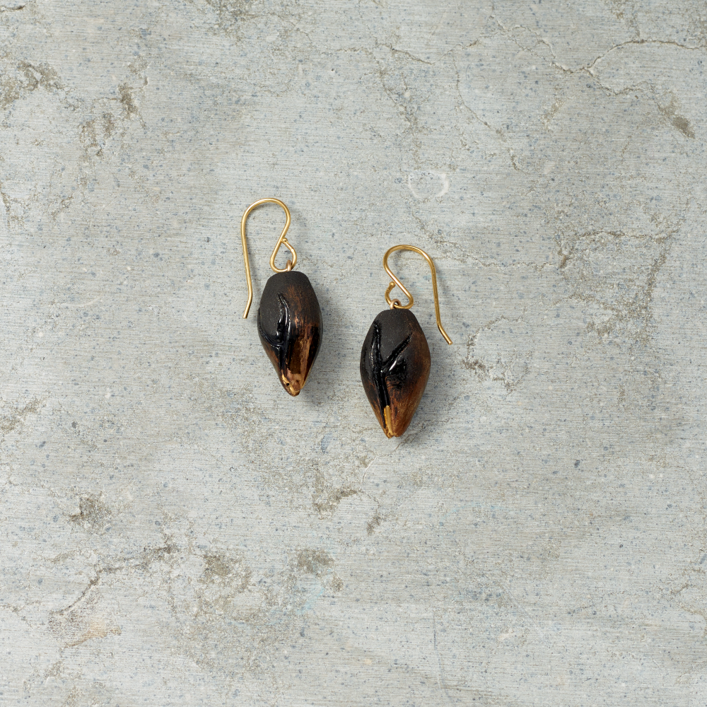 Pair of gold and black earrings on a textured gray surface