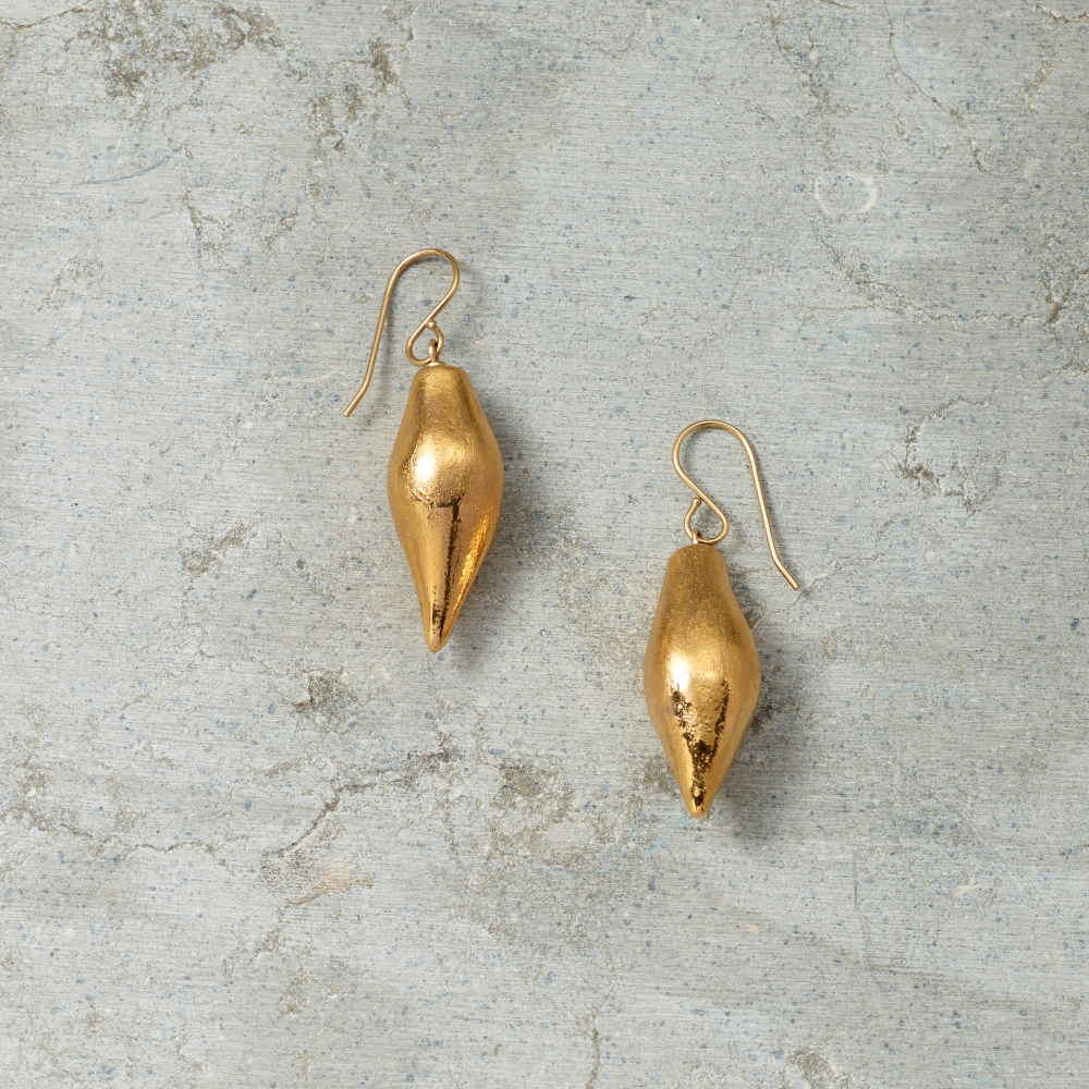 Pair of gold earrings on a textured gray surface
