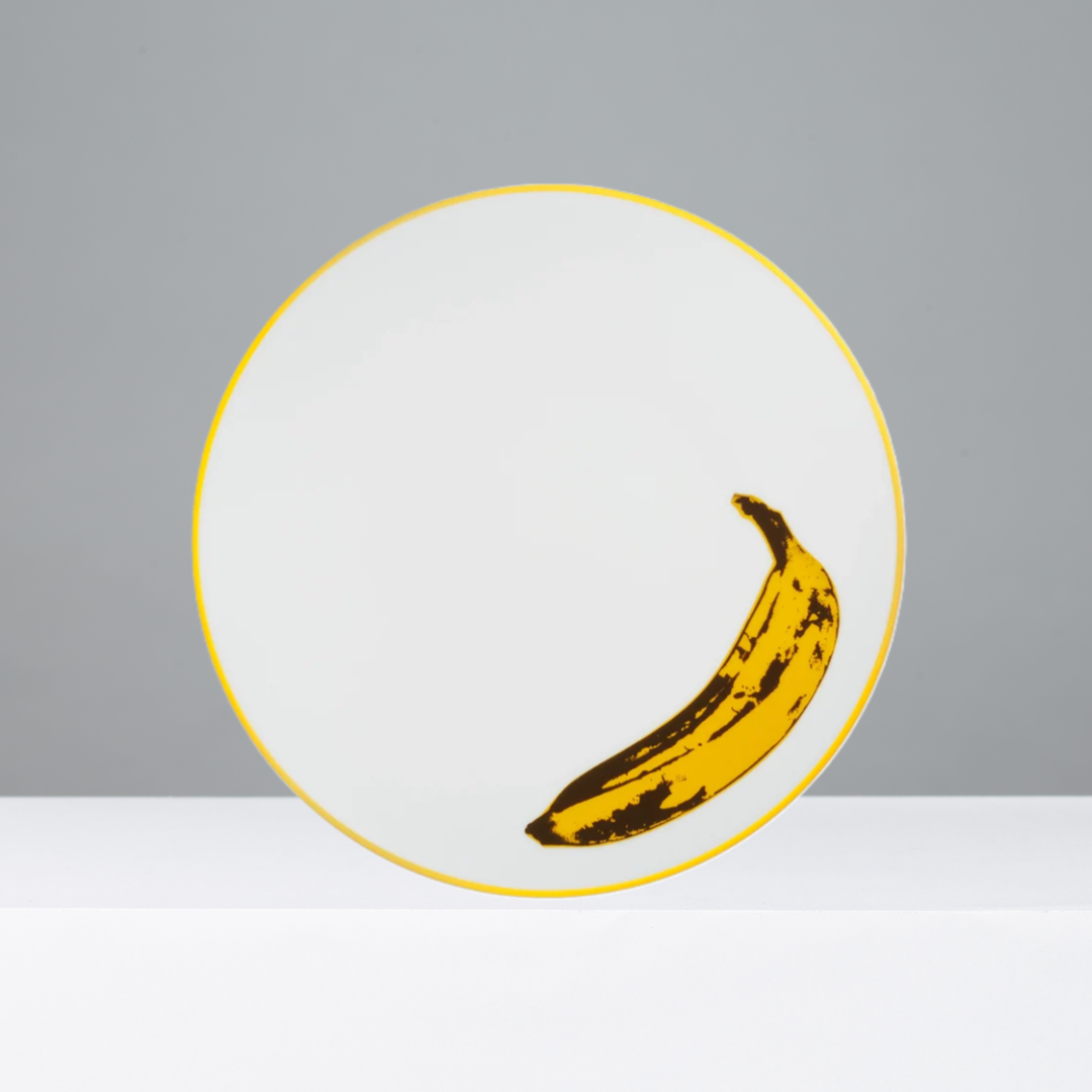 White plate with a yellow banana illustration on a gray background