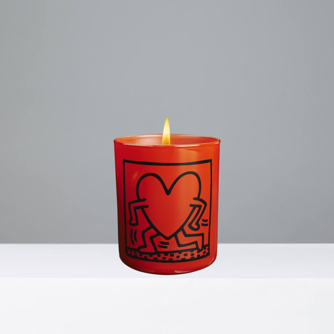 Red candle with a black heart design on a gray background