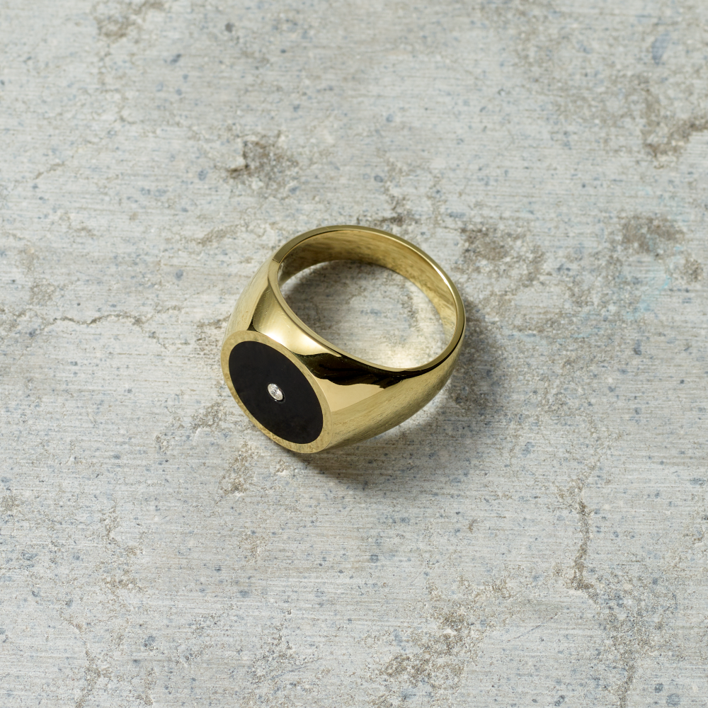 Gold ring with a black center on a textured gray surface