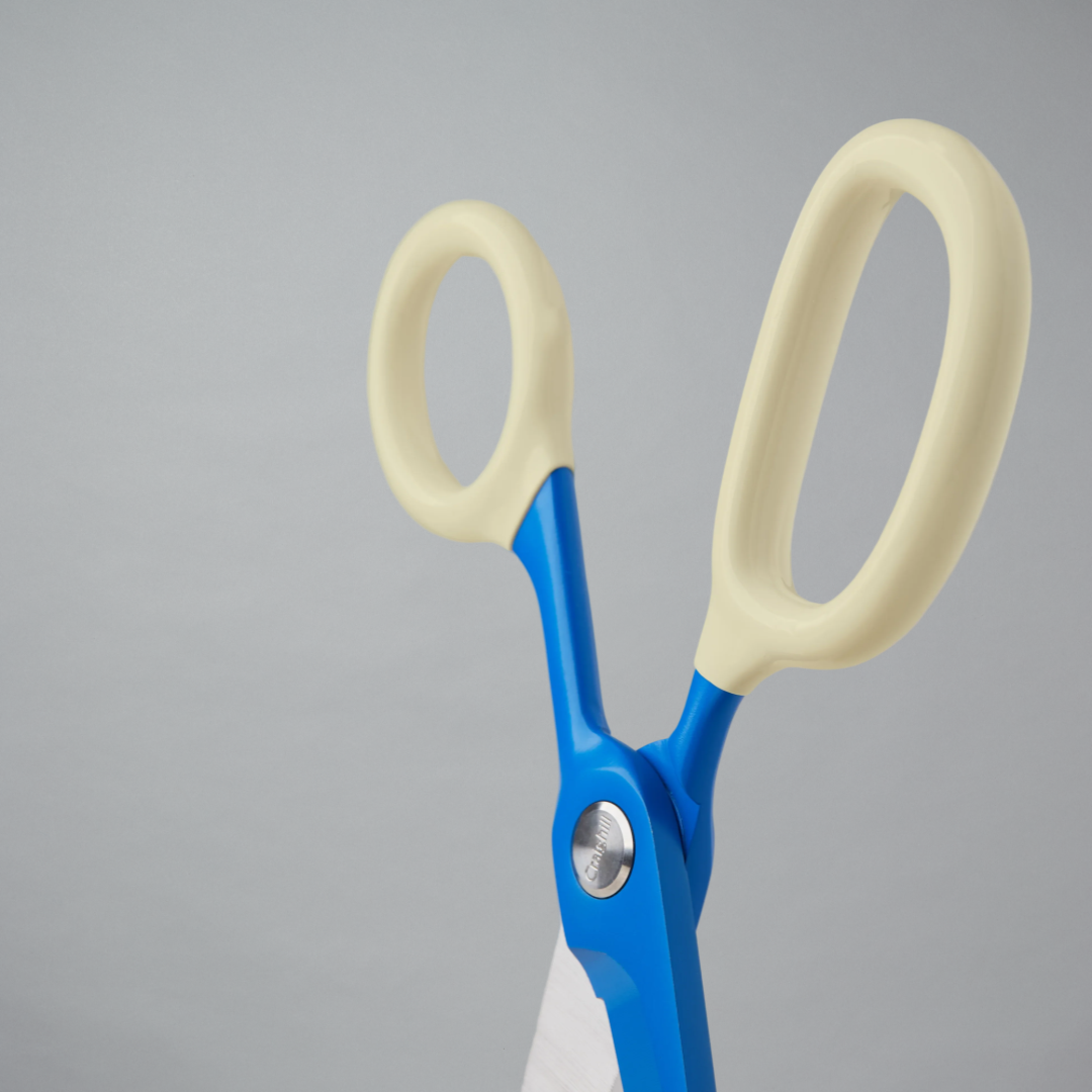 Pair of blue scissors with white handles on a gray background