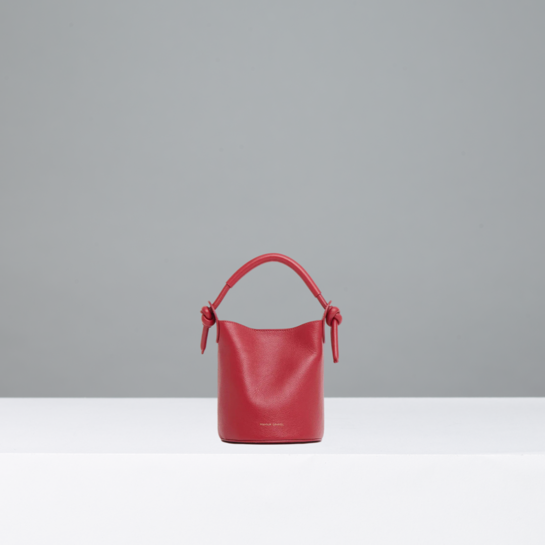 Red handbag with a knot detail on a gray background