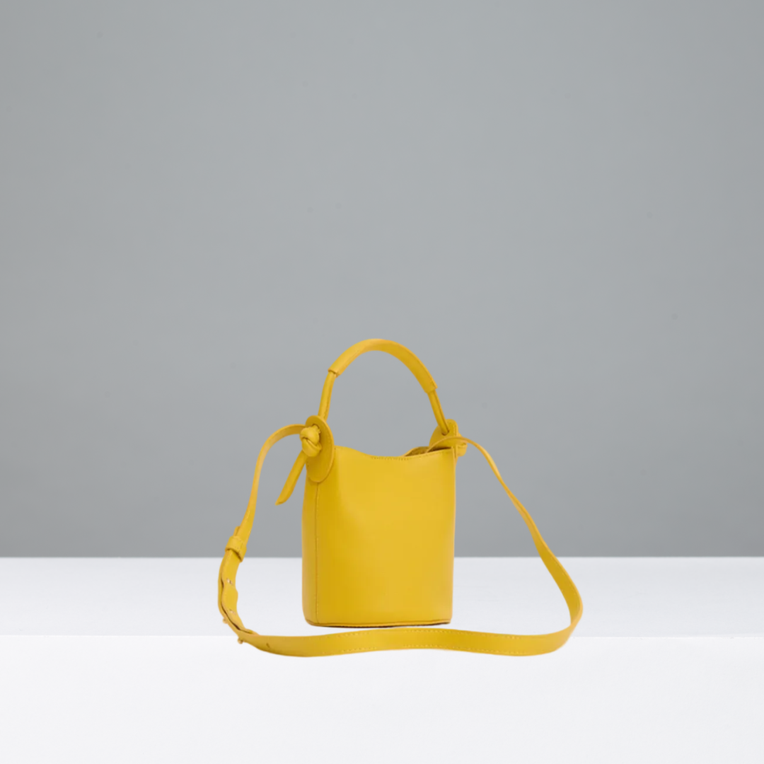 Yellow handbag with a strap on a gray background