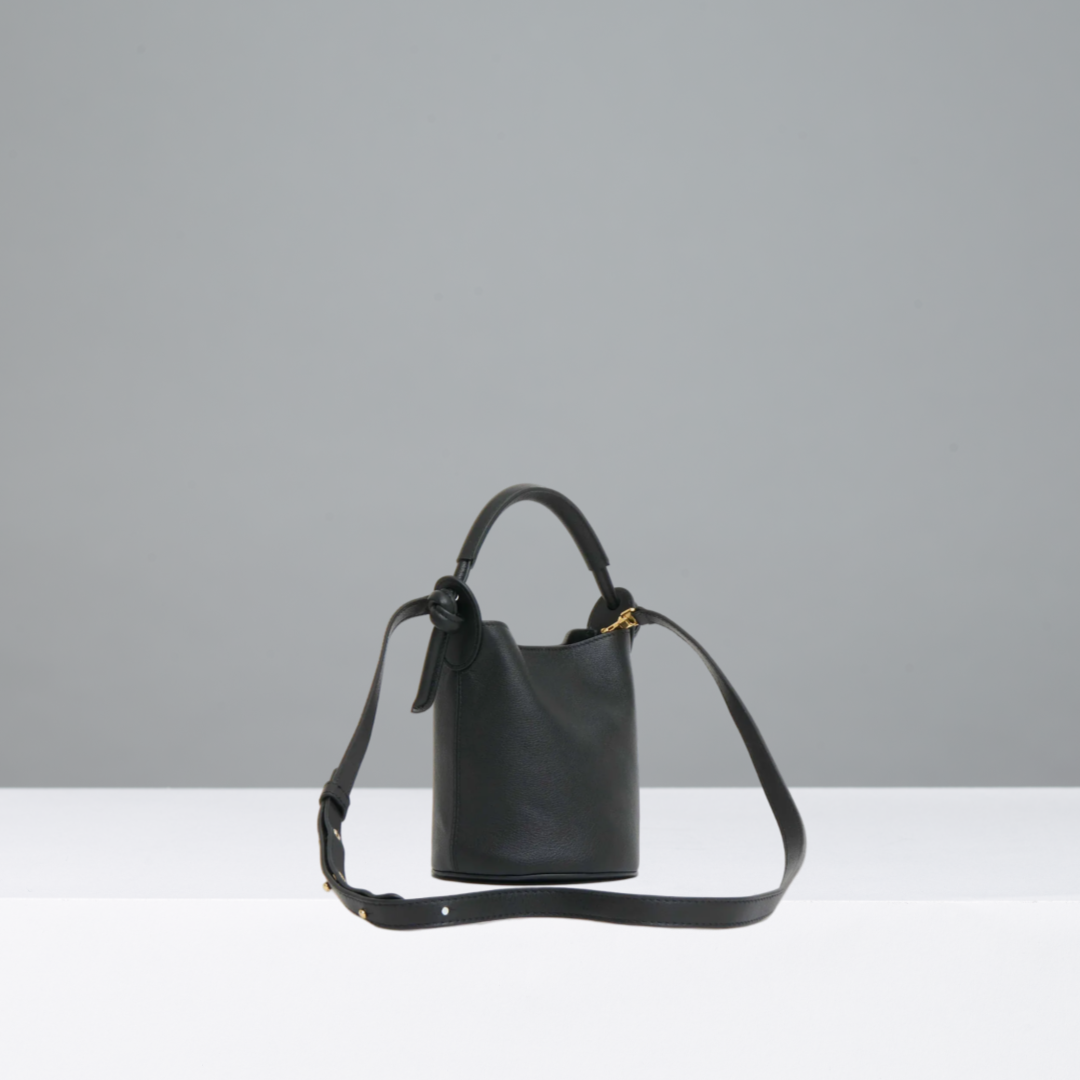 Black leather handbag with a strap on a gray background