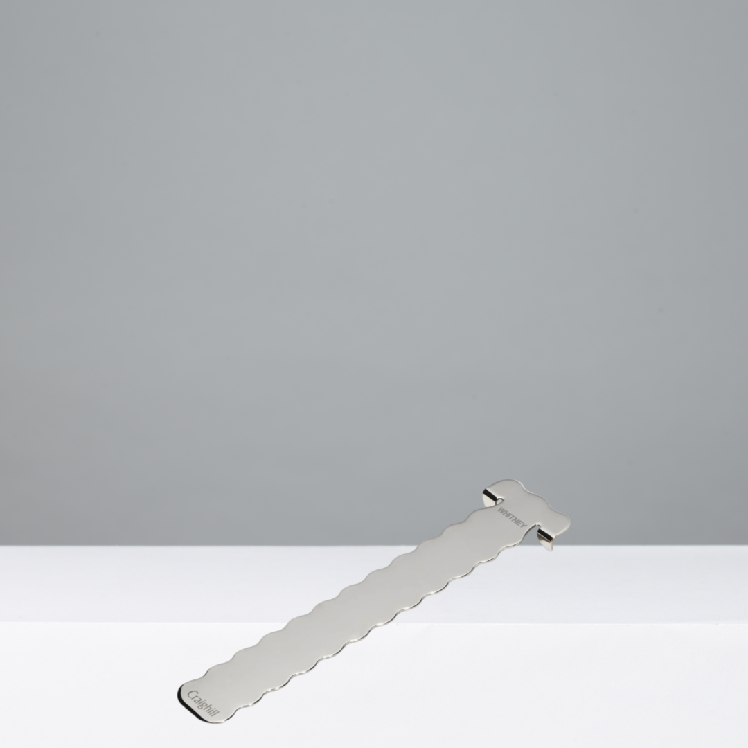 Silver bookmark with a wavy design on a gray background