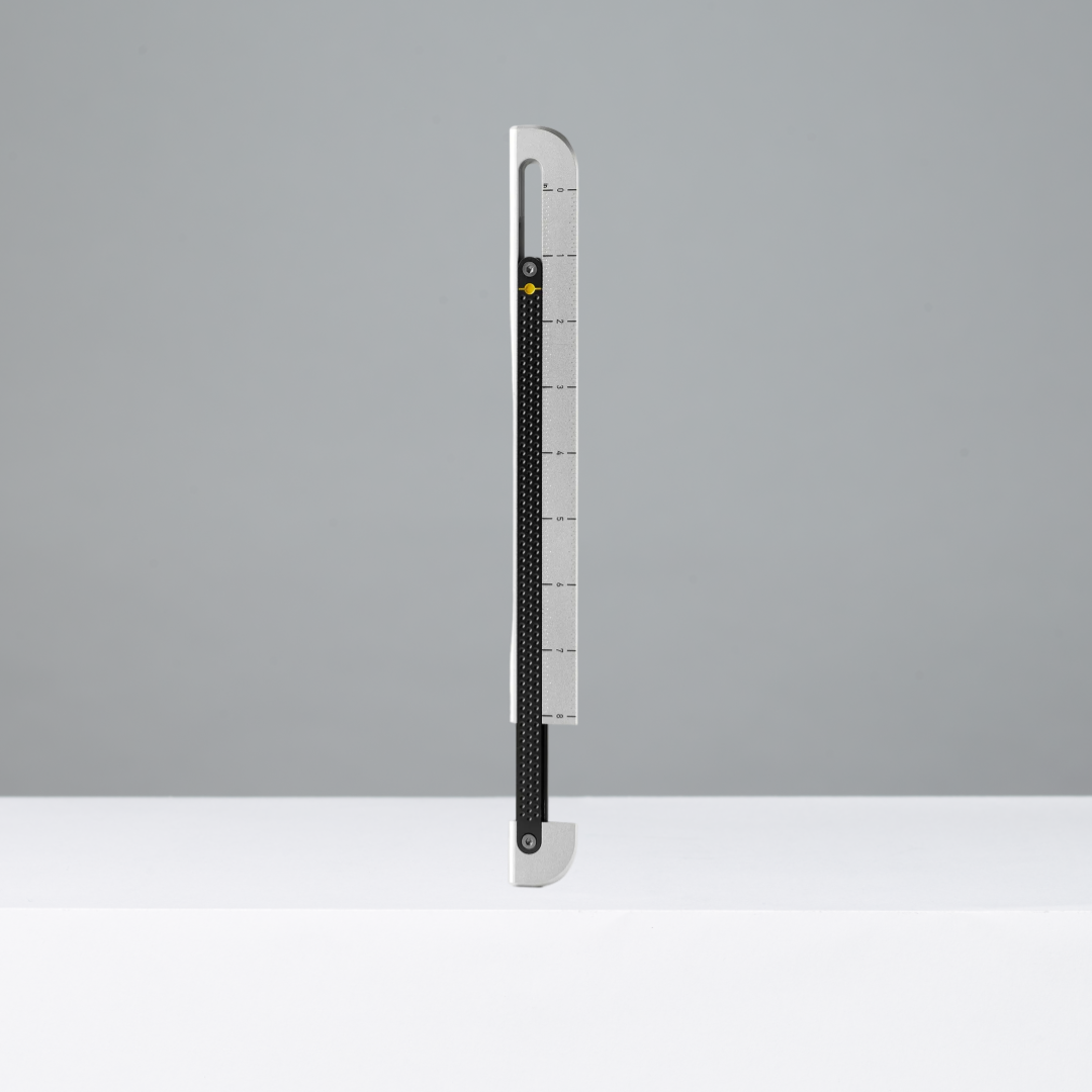 Tall, thin ruler with measurement markings on a gray background