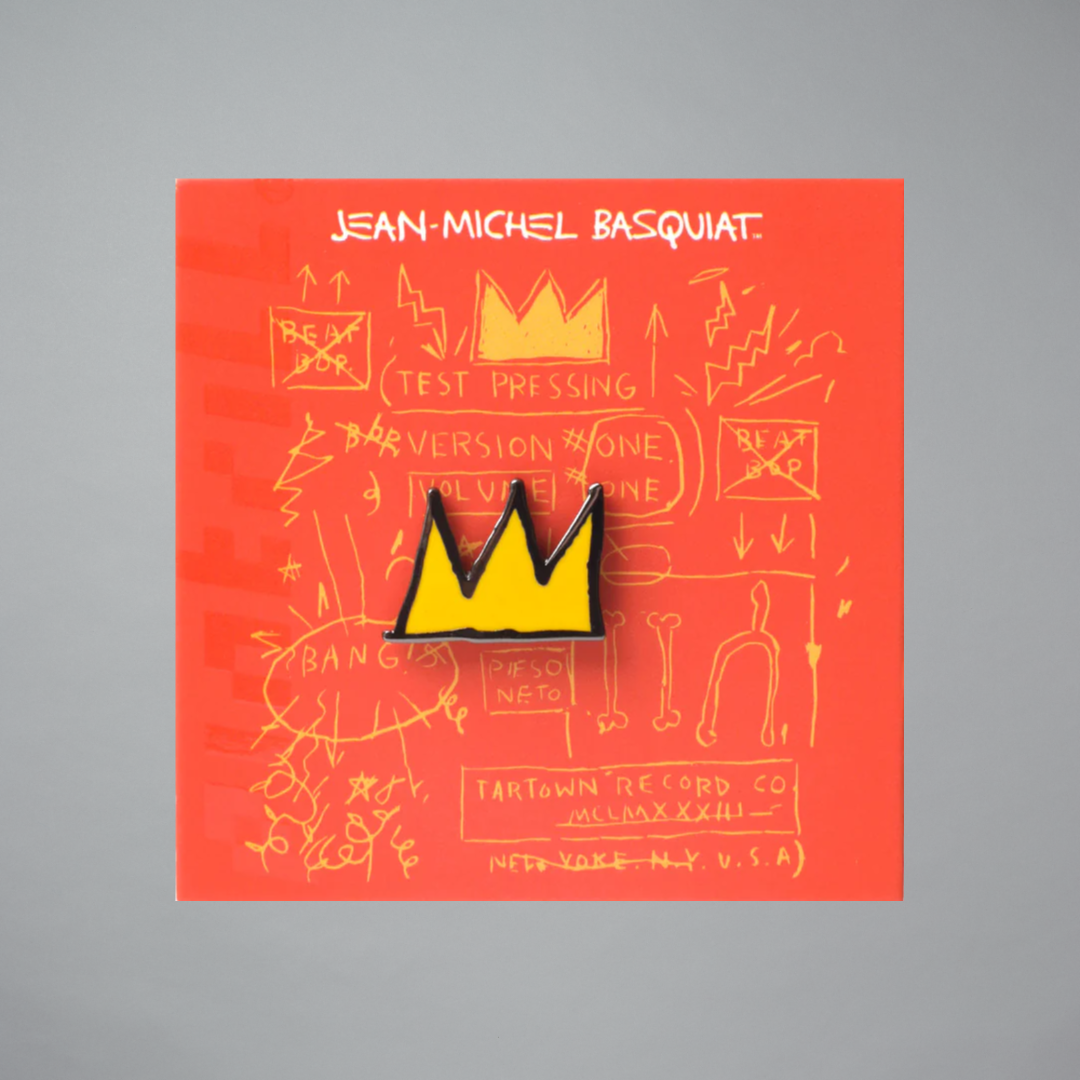 Pin with yellow crown design on a red card featuring Jean-Michel Basquiat text and graphics.