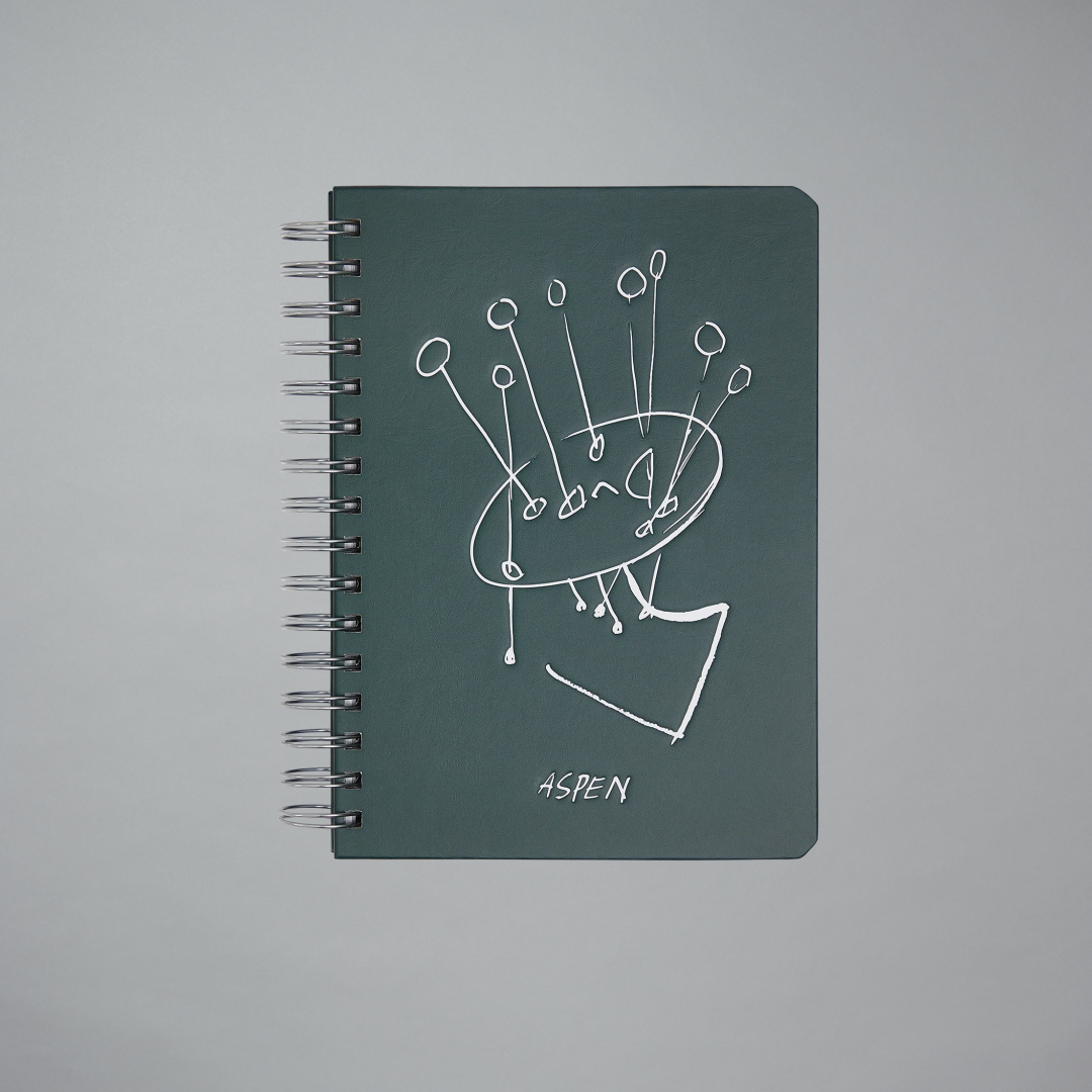 Green notebook with white line art design on a gray background