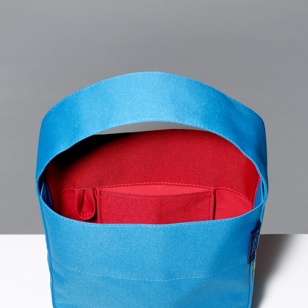 Blue bucket bag with a red interior on a gray background