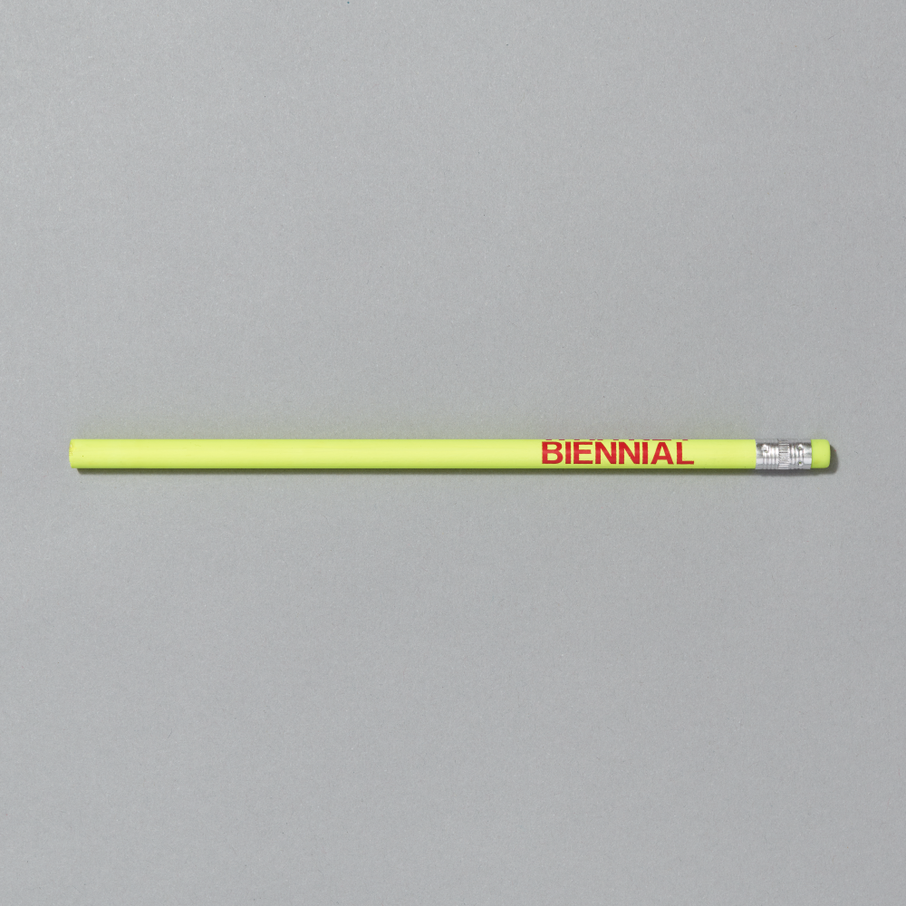Yellow pencil with 'BIENNIAL' text on a gray background