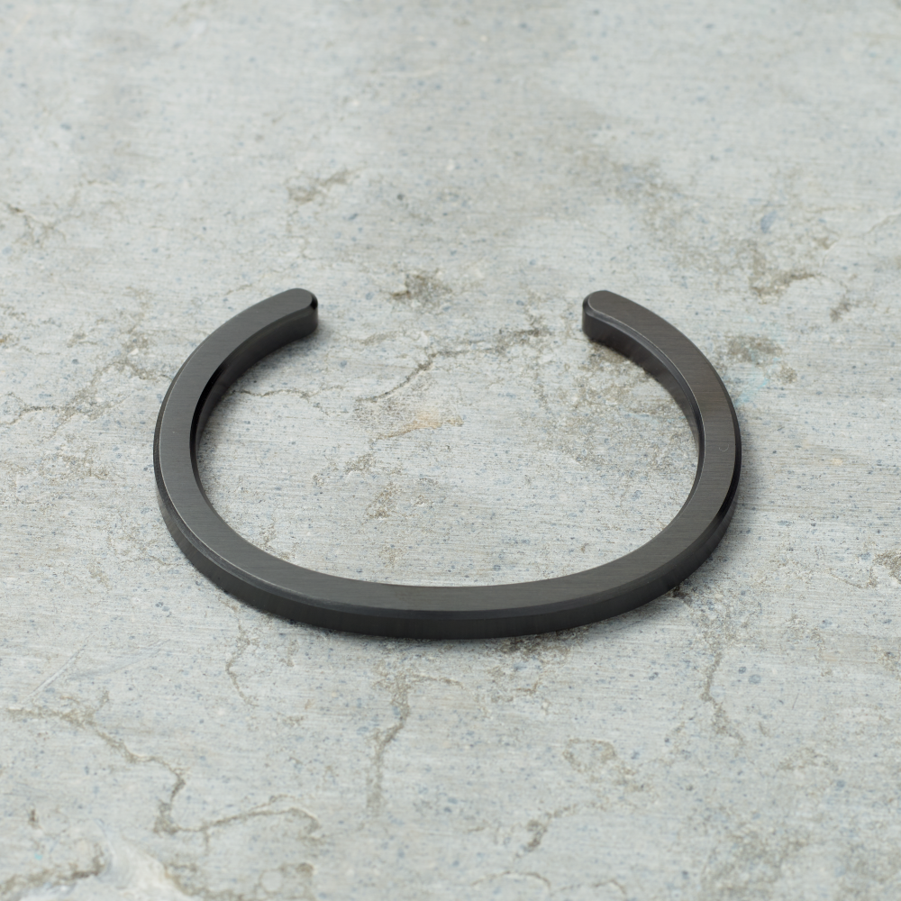 Black metal bracelet on a textured gray surface
