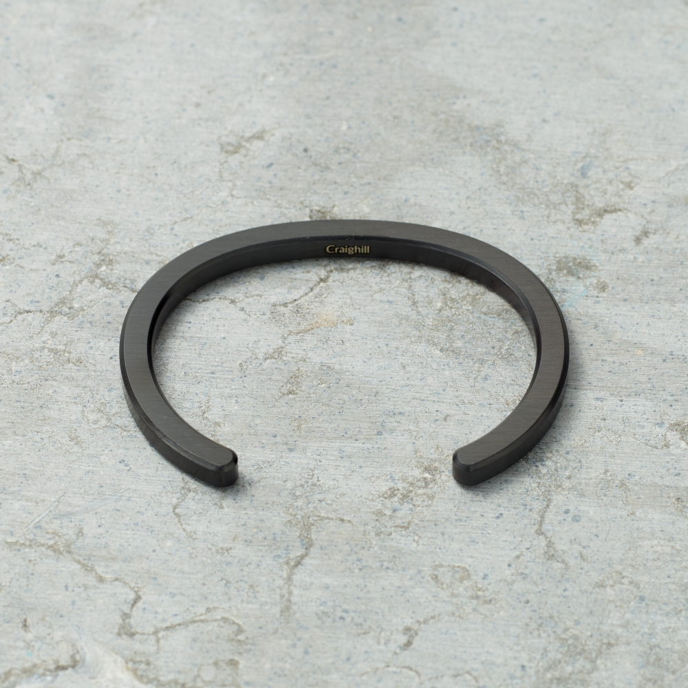 Black metal bracelet on a textured gray surface