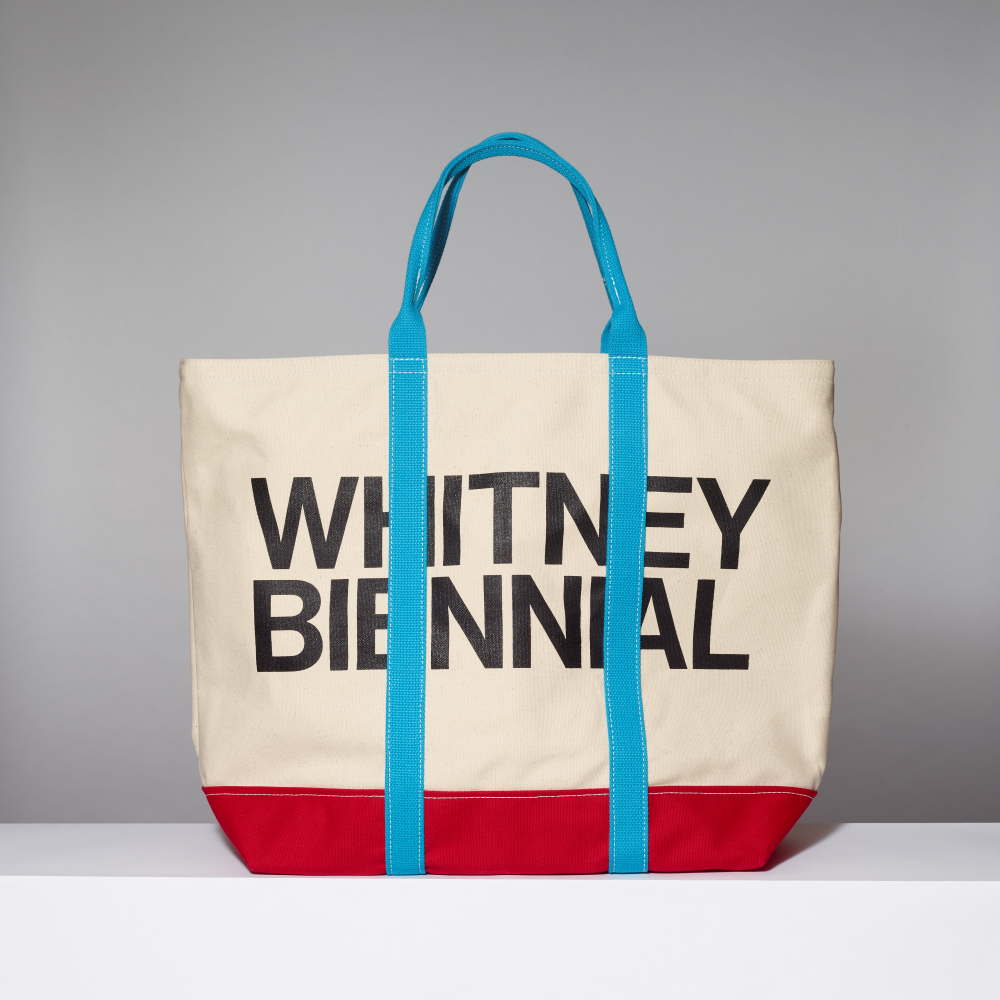 Tote bag with 'WHITNEY BIENNIAL' text on a gray background