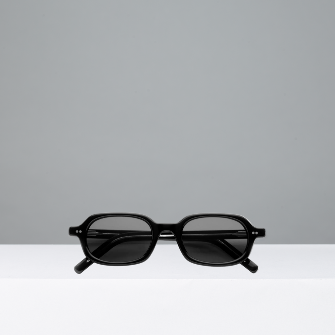 Black sunglasses on a white surface with a gray background
